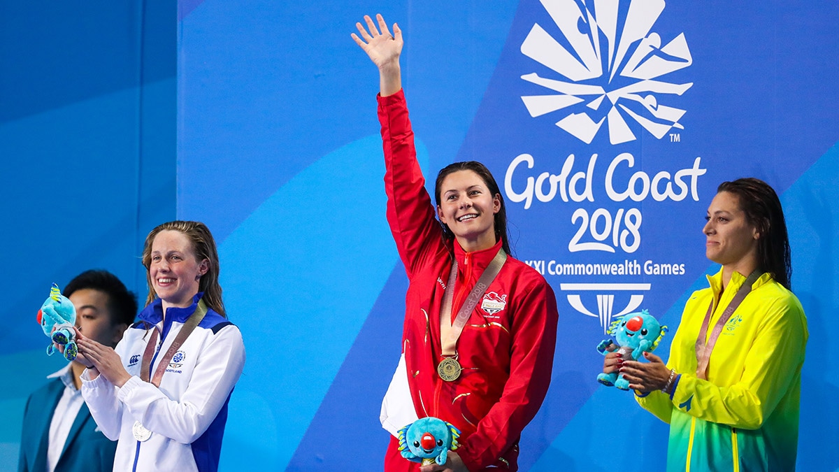 Aimee Willmott waves to the crowd as she stands on top of the podium at the 2018 Commonwealth Games